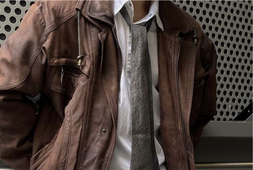 Brown leather jacket with a white top and army green tie